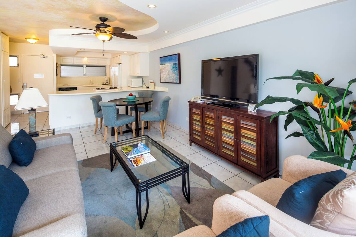 Uma sala de estar com sofá, mesa de centro, TV e um espaço de jantar com cadeiras e mesa.