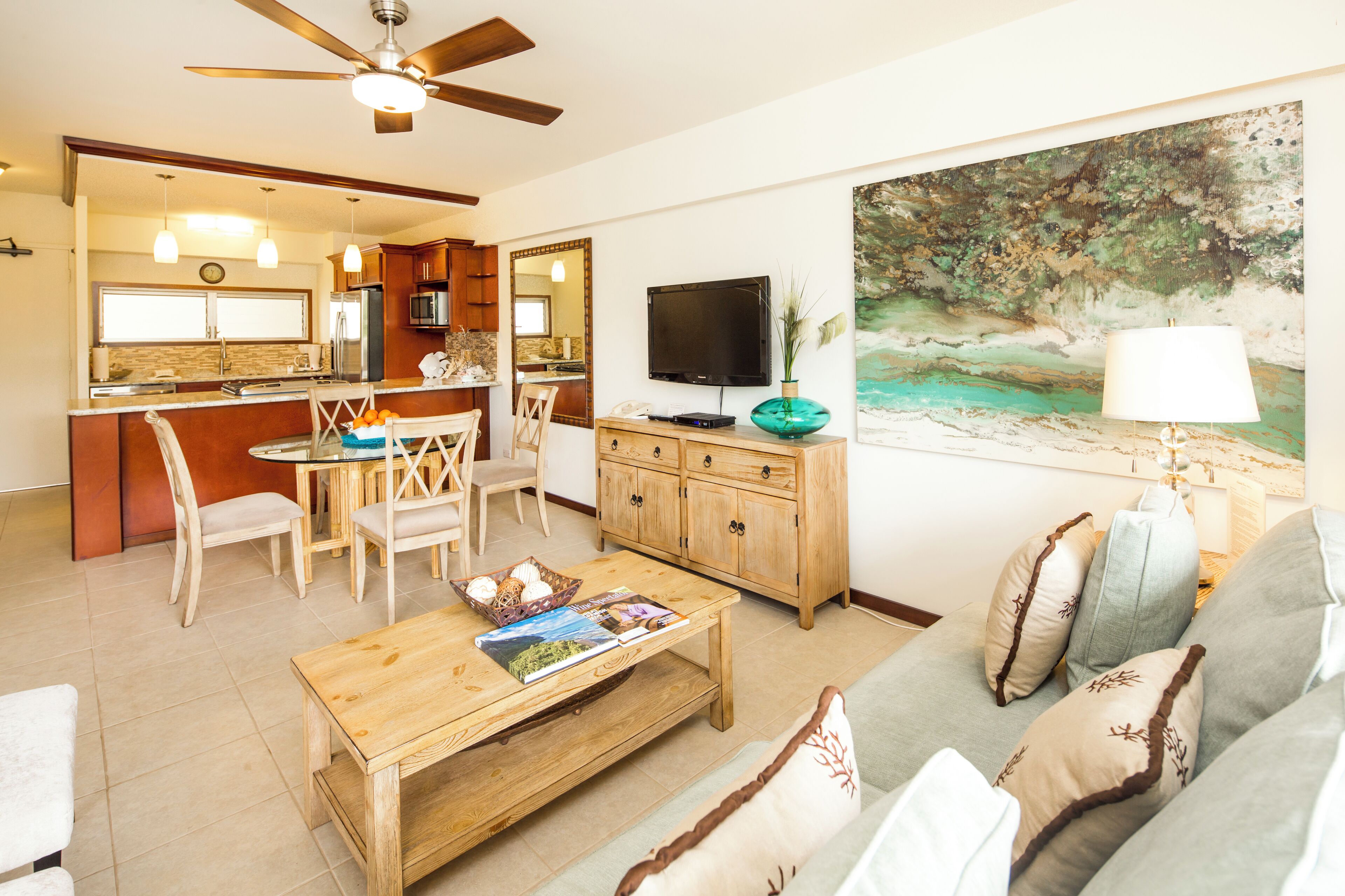 A modern living room with a dining area, a kitchen in the background, and a large painting on the wall.