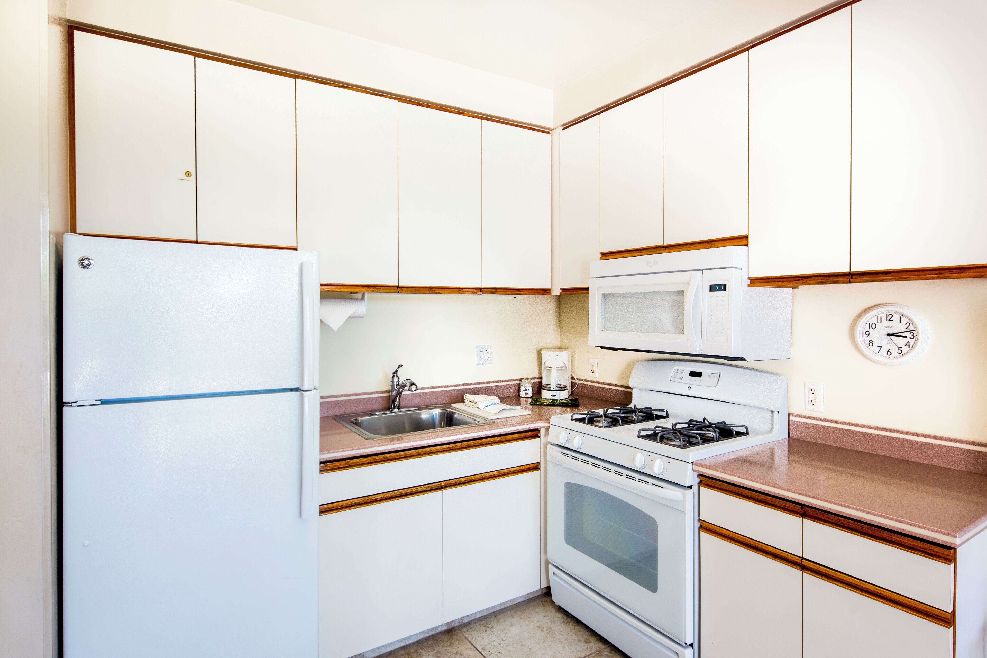 A compact kitchen with a refrigerator, stove, microwave, and sink.