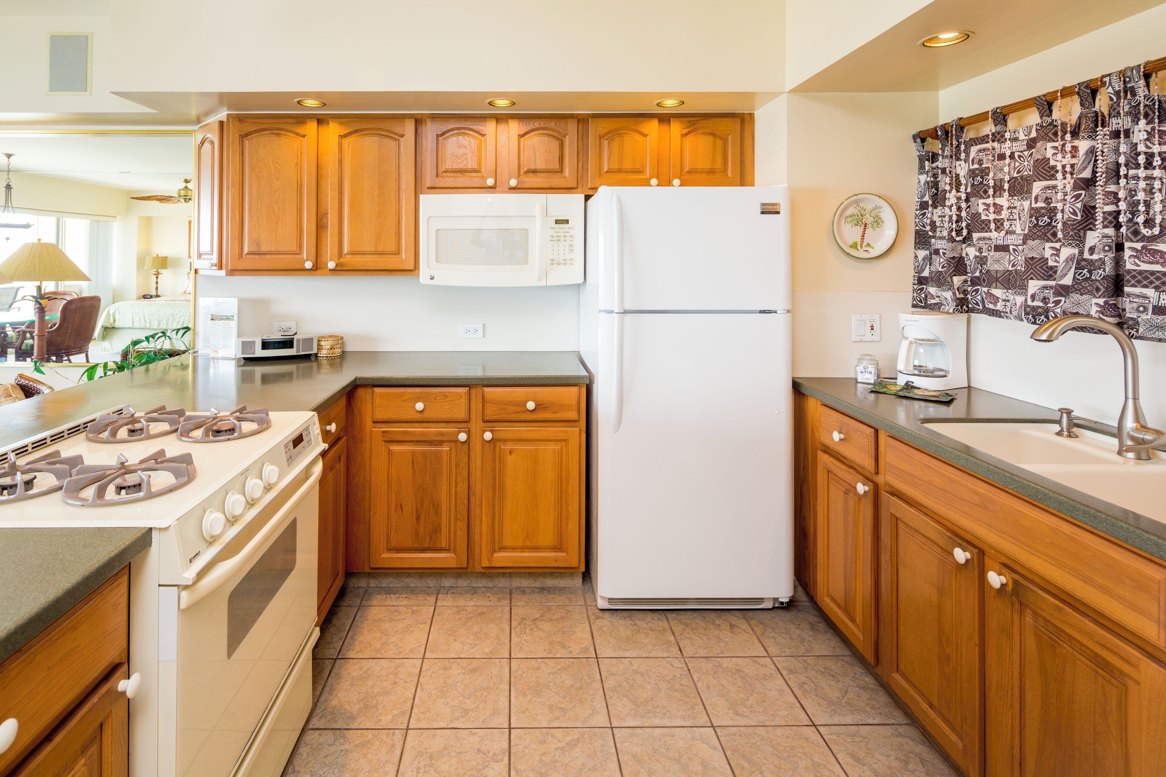 A kitchen with wooden cabinets, a white stove, a microwave, and a refrigerator.