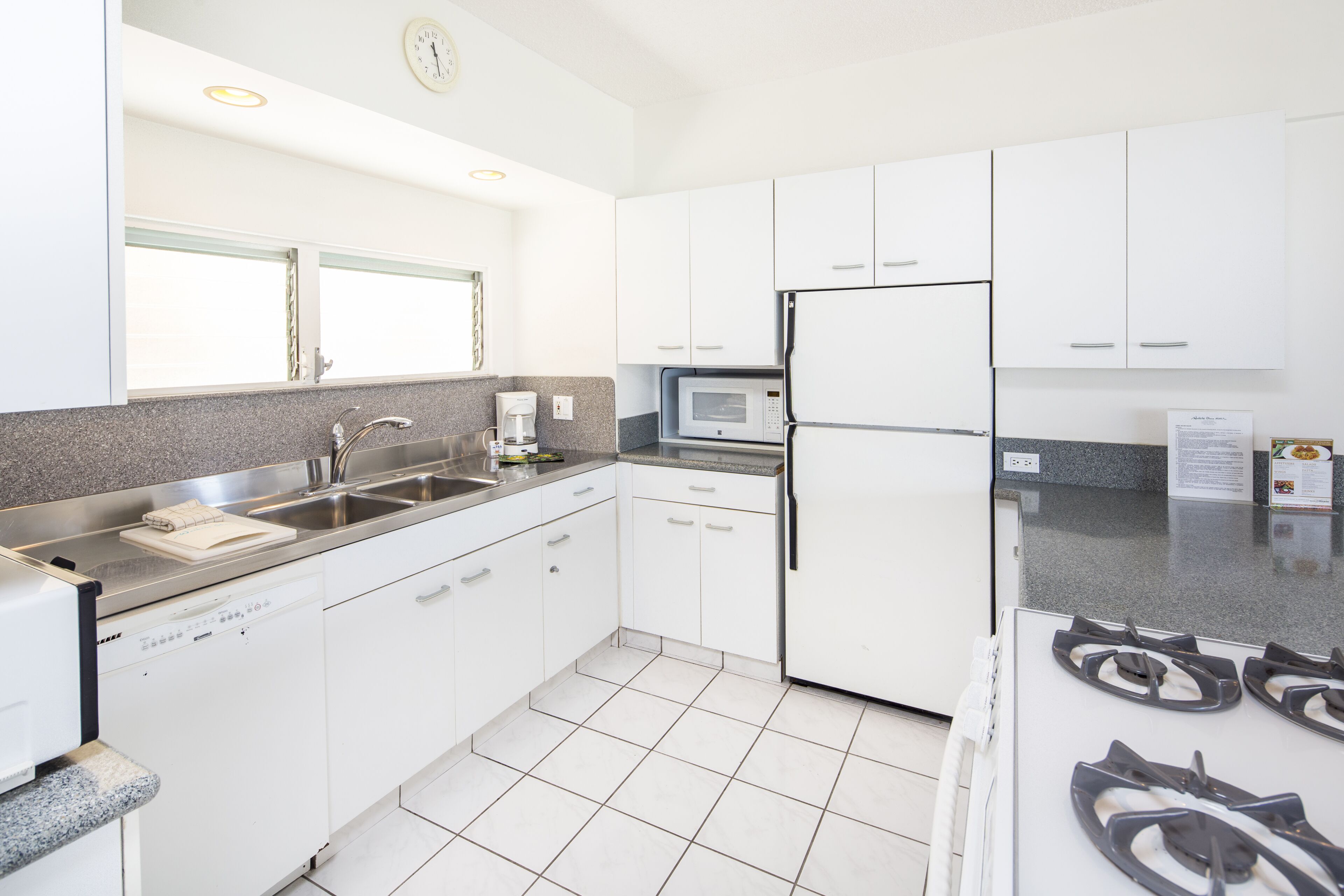 A modern kitchen with white cabinets, a built-in microwave, a refrigerator, and a gas stove.