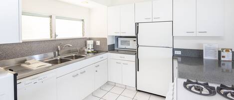 A modern kitchen with white cabinets, a built-in microwave, a refrigerator, and a gas stove.