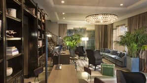 A modern hotel lobby with a long dining table, comfortable seating, a chandelier, and a staircase. - The Shepley South Beach Hotel (Miami Beach)