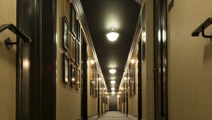 A long, narrow hotel hallway with multiple doors on either side, a carpeted floor, and a series of lights along the ceiling. - The Shepley South Beach Hotel (Miami Beach)
