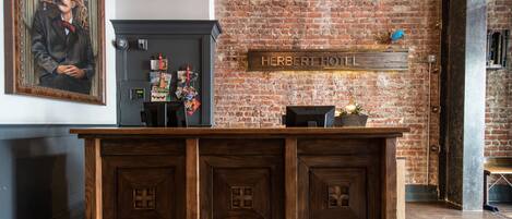 Un mostrador de recepción con detalles de madera, un reloj y un letrero que dice "HERBERT HOTEL".
