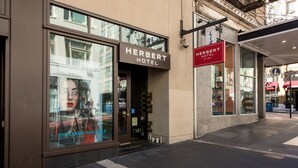 La façade de l’hôtel Herbert, avec une grande fenêtre où est affichée une publicité pour des examens de la vue.