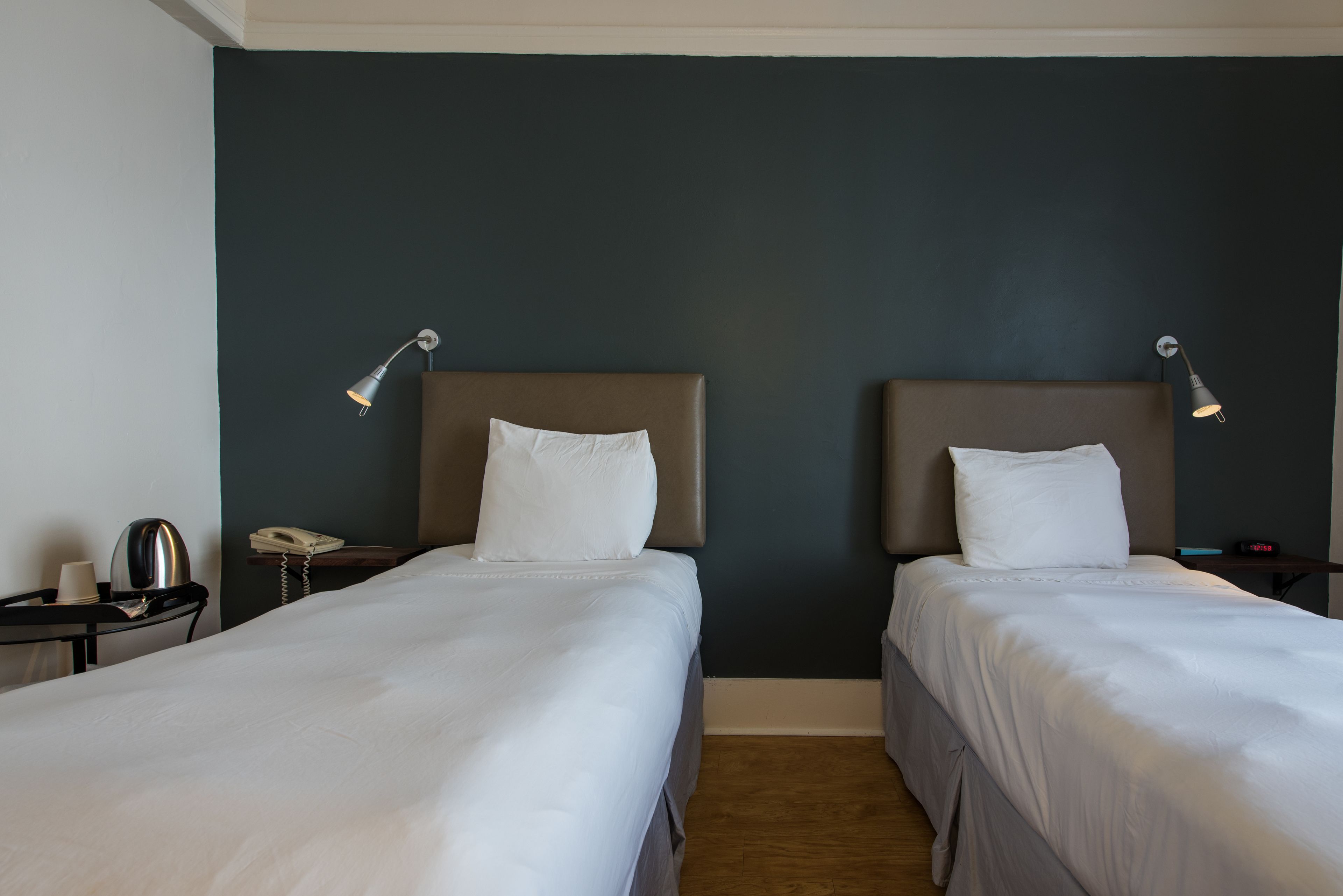 A hotel room with two beds, a desk, a telephone, and a lamp.
