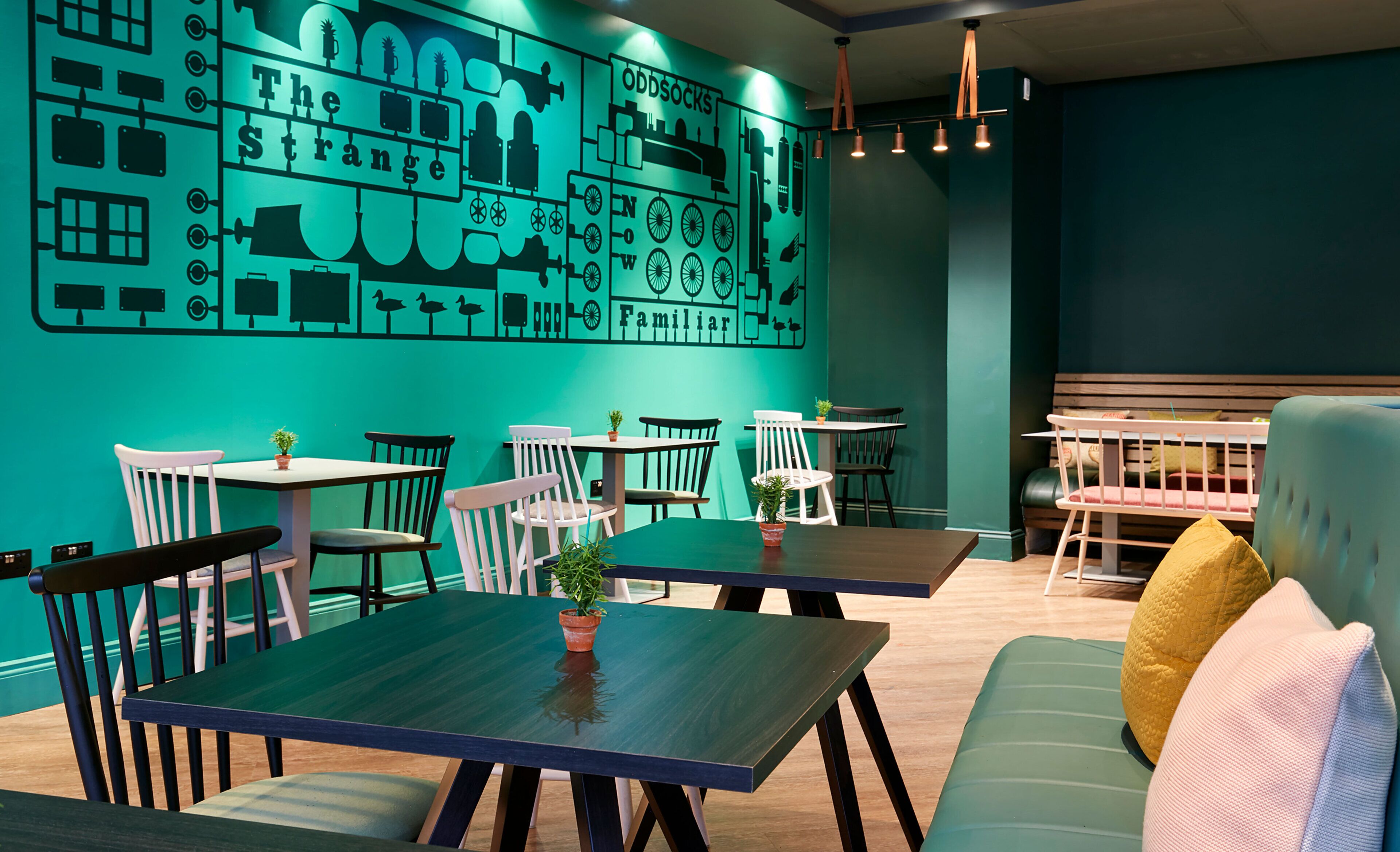 A restaurant with teal walls, wooden tables, and chairs.