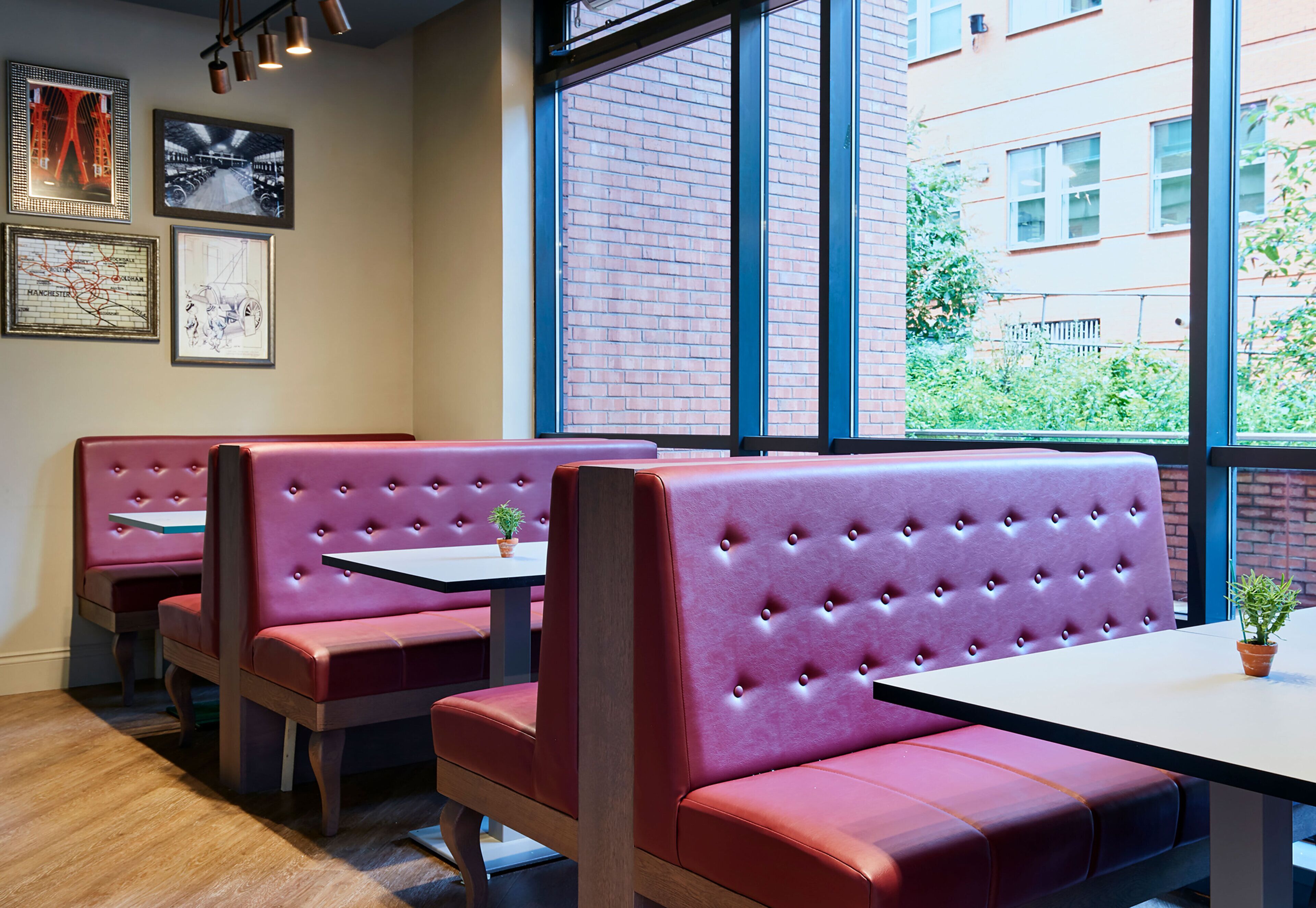 A restaurant interior with red cushioned booths, wooden tables, and large windows offering a view of the outside.