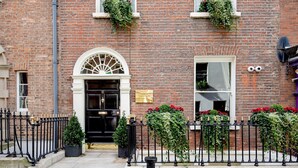 A brick building with a black door, white window frames, and a black metal fence. - Trinity Townhouse Hotel (Dublin)