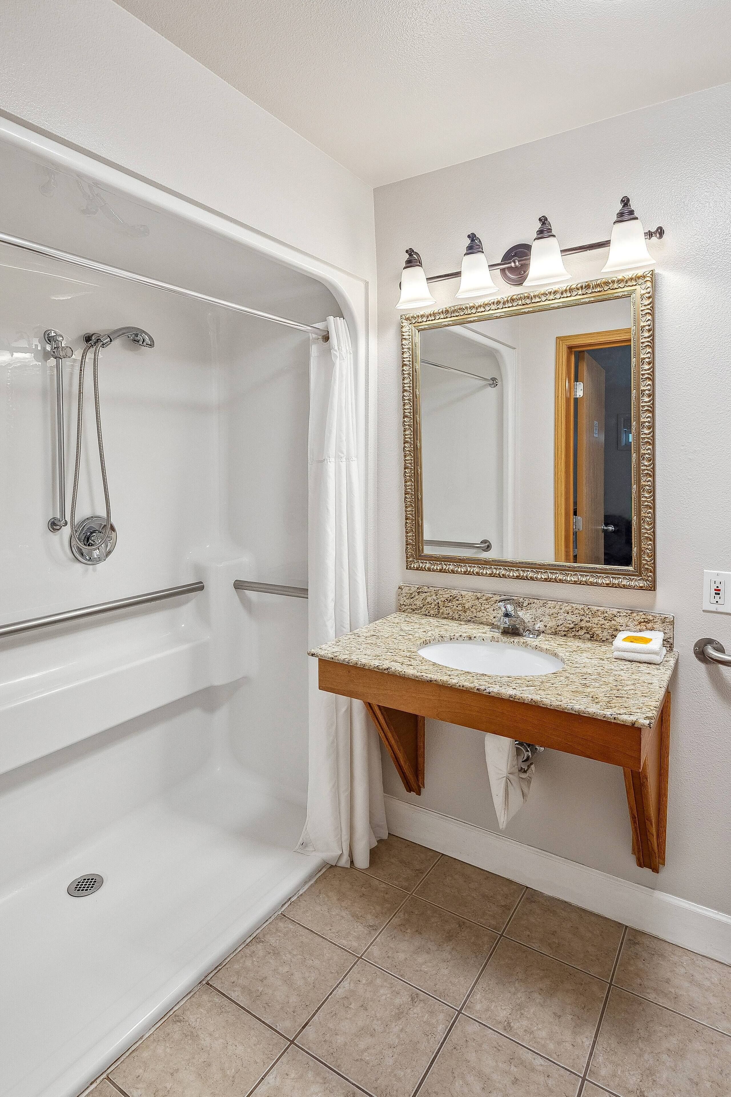 A bathroom with a white bathtub, a sink with a mirror, and a shower with a glass door.
