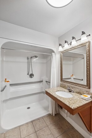 A bathroom with a bathtub, a sink, a mirror, and a shower curtain. - Hotel Edgewater (Seward)