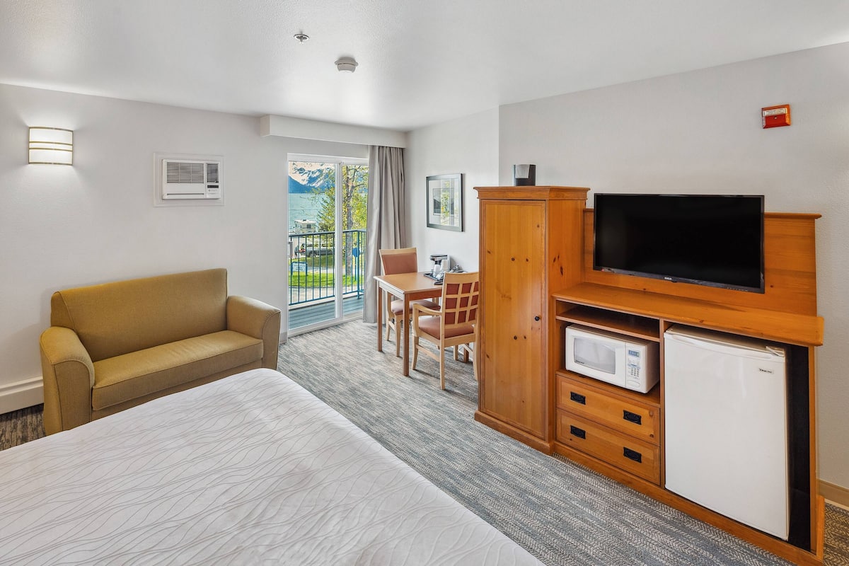 Une chambre d’hôtel équipée d’un lit, d’un canapé, d’une télévision, d’un four à micro-ondes et d’un petit réfrigérateur.