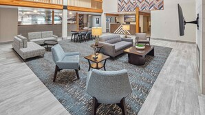 A spacious lobby with a high ceiling, a reception desk, and a seating area with sofas and chairs.