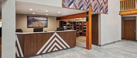 A reception area with a modern design, featuring a chevron-patterned wall, a reception desk, and a view of the cityscape through the window.