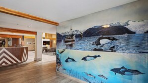 A lobby with a large mural of marine life and a wooden reception desk.