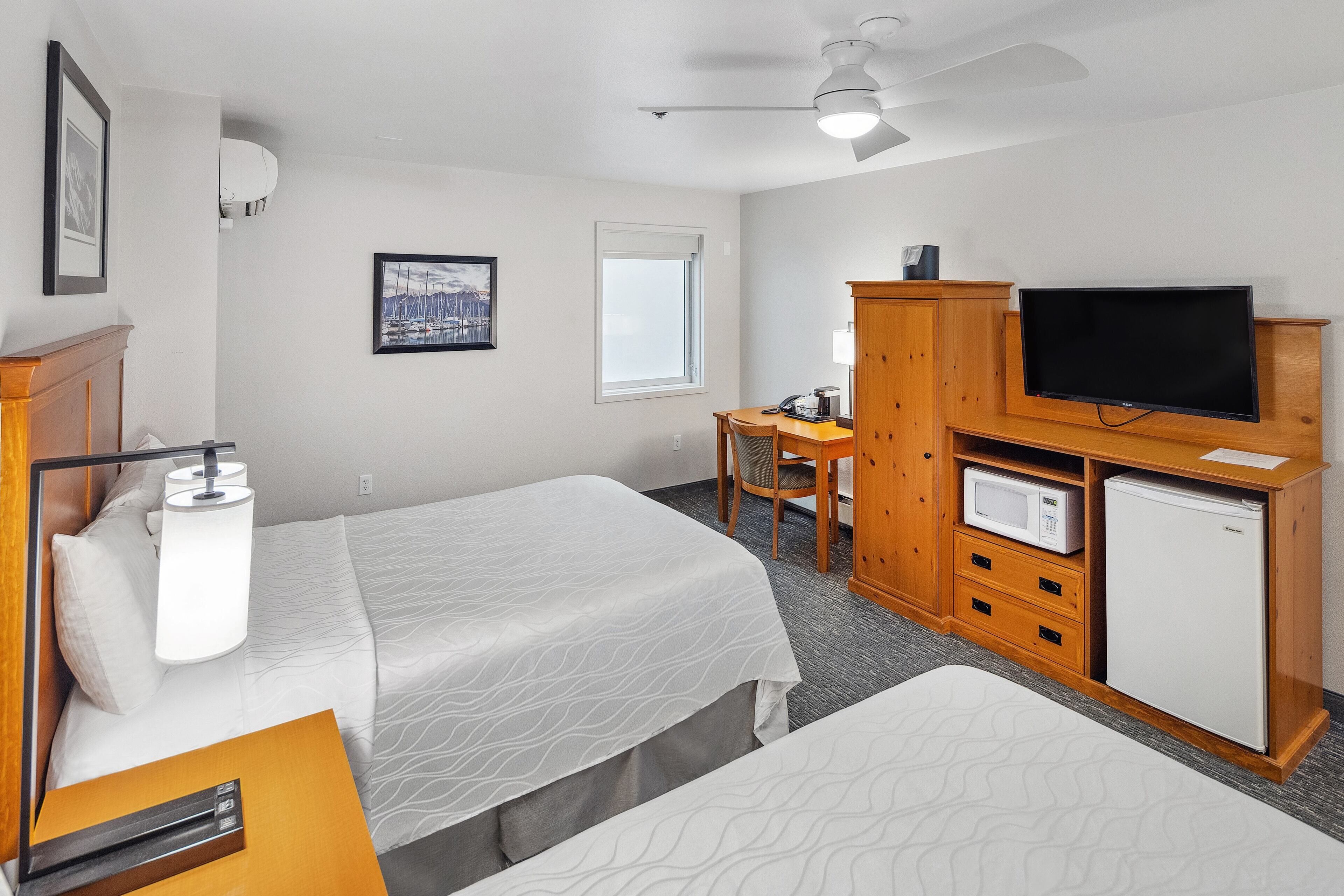 Een hotelkamer met twee bedden, een bureau, een televisie, een magnetron en een koelkast.