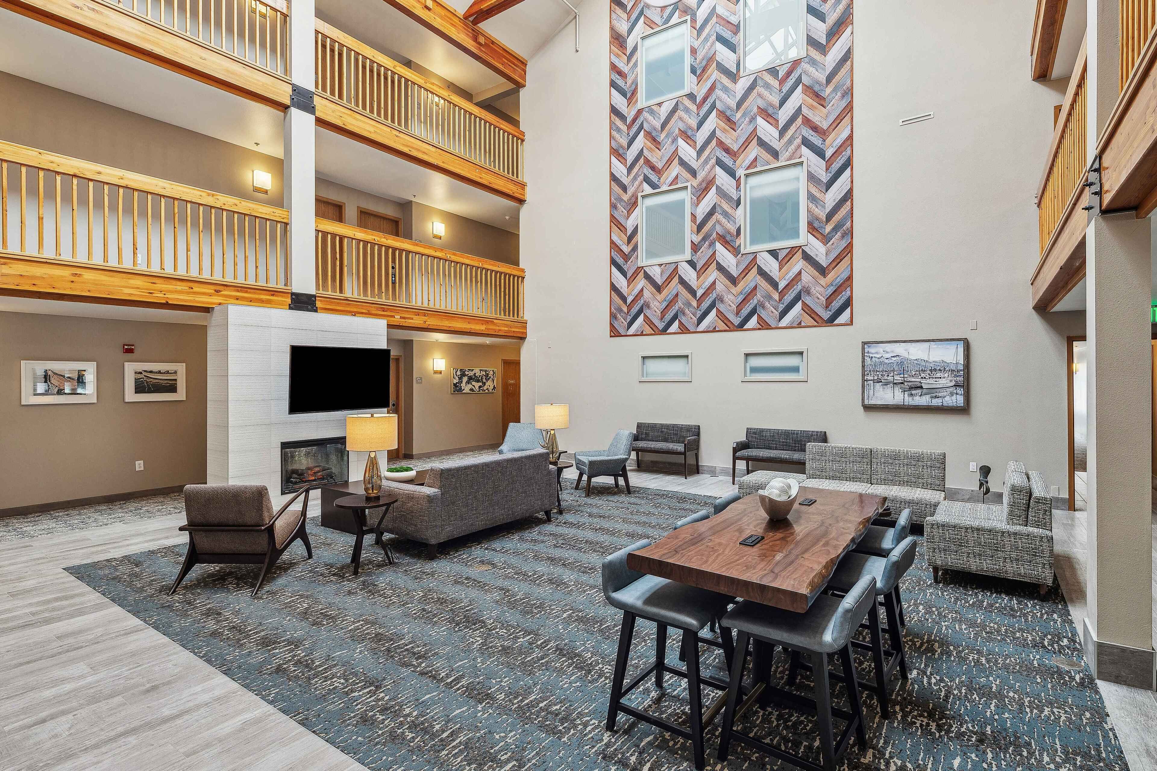 A spacious lobby with a high ceiling, a fireplace, multiple seating areas, and a large wall with a geometric pattern.