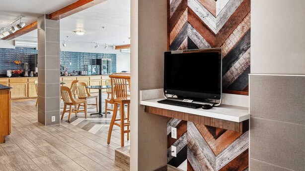 A modern kitchen with a built-in TV, wooden flooring, and a herringbone-patterned backsplash.
