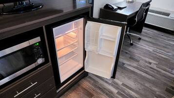 A compact kitchen with a microwave, a small refrigerator, and a wooden countertop.