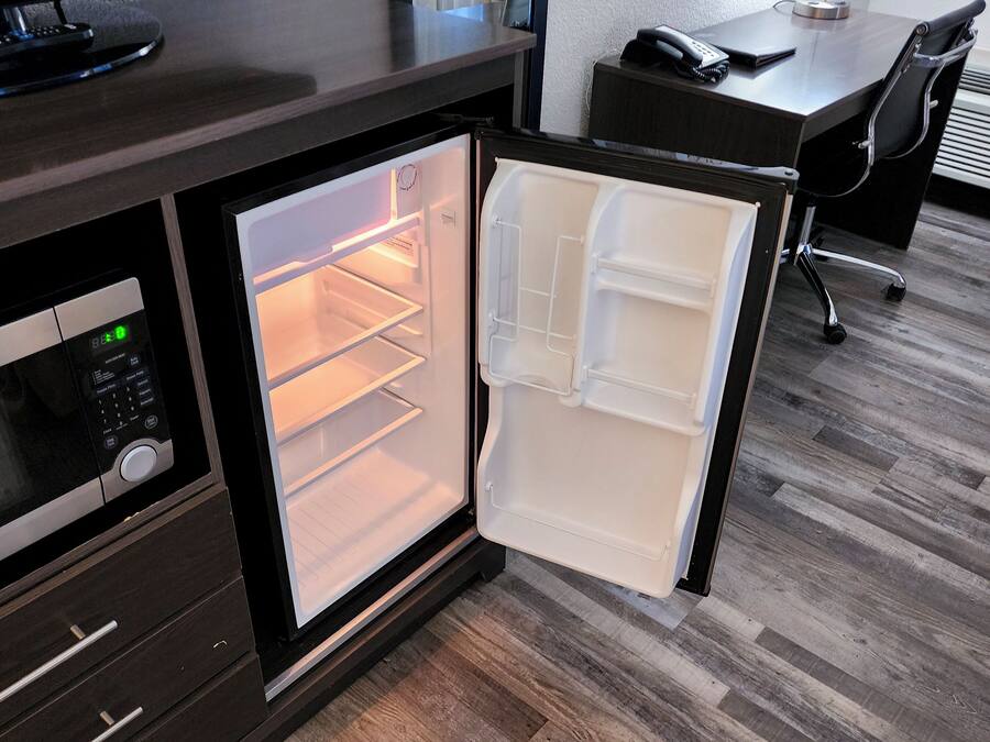 A compact kitchen with a microwave, a small refrigerator, and a wooden countertop.