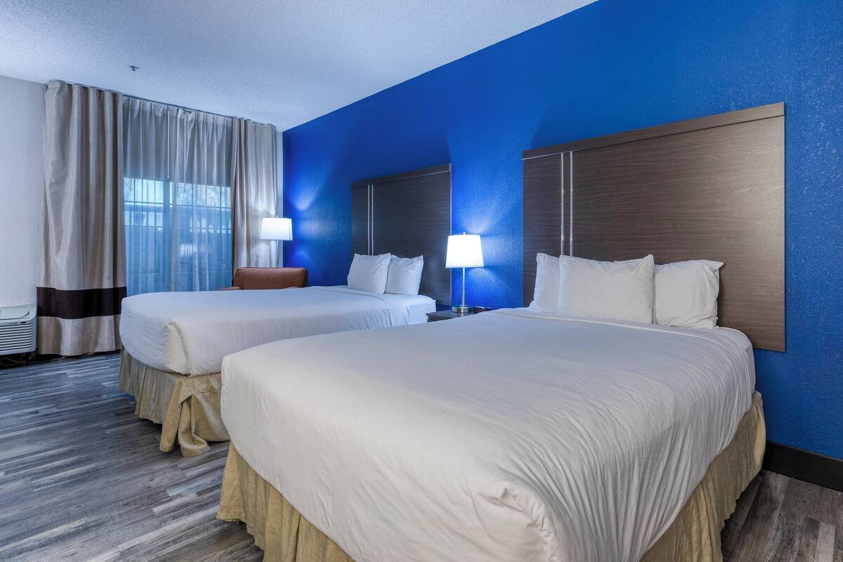 Ein Hotelzimmer mit zwei Betten, einem großen Spiegel und einer blauen Wand.