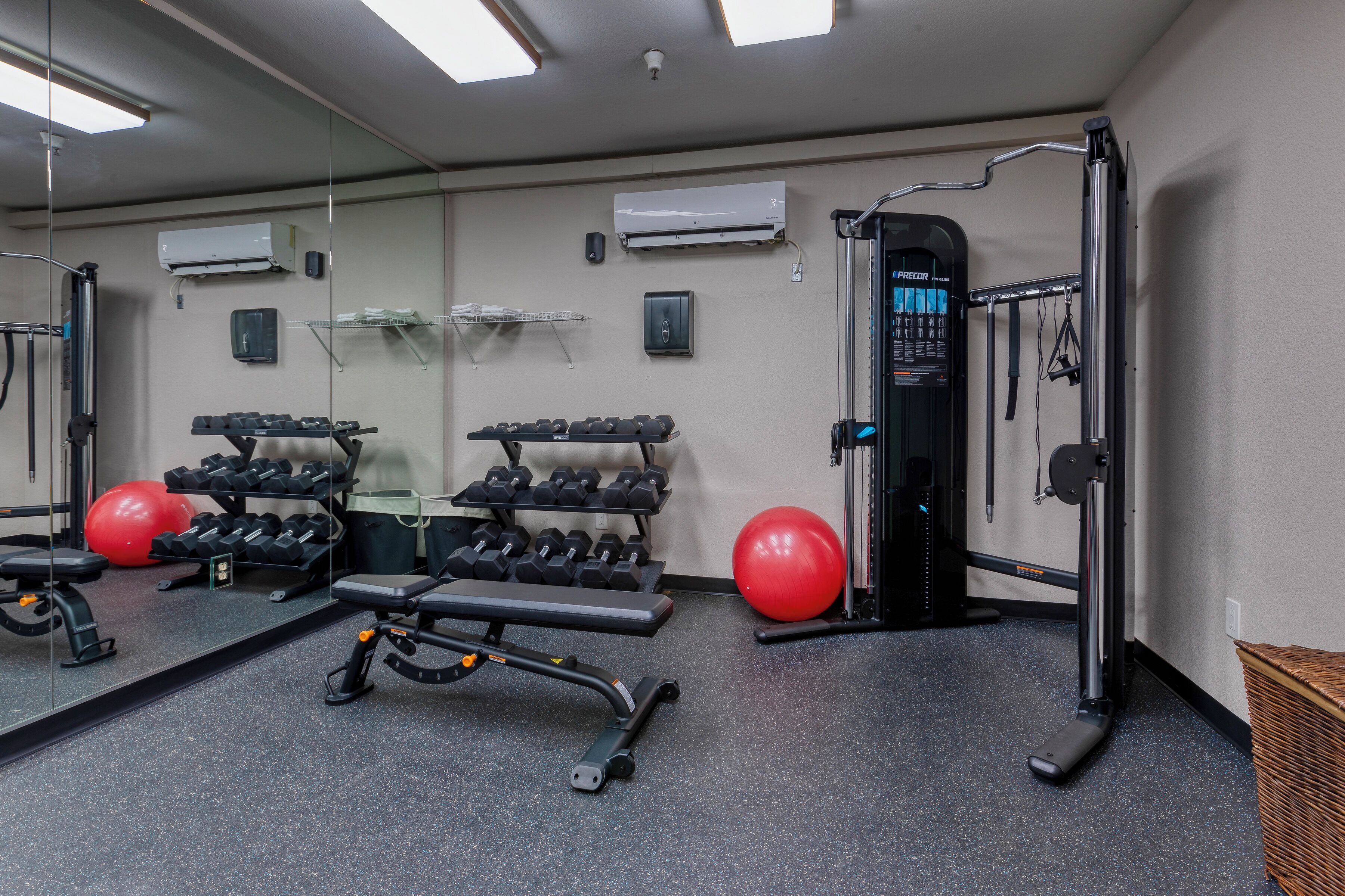 A gym with exercise equipment, a mirror, and a red exercise ball.