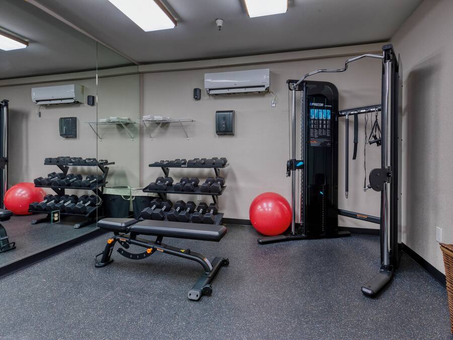 A gym with exercise equipment, a mirror, and a red exercise ball.