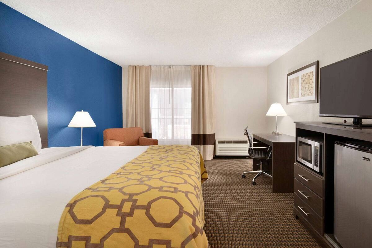 Ein Hotelzimmer mit Bett, Schreibtisch, Stuhl, Fernseher und Minibar.