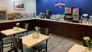 Ein Frühstücksbereich mit Tresen, Kaffeeautomaten und einem Wandzeichen mit der Aufschrift 'Baymont Breakfast Corner'.