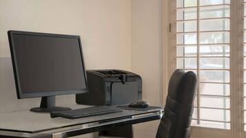 Een computerbureau met een monitor, toetsenbord en een printer.