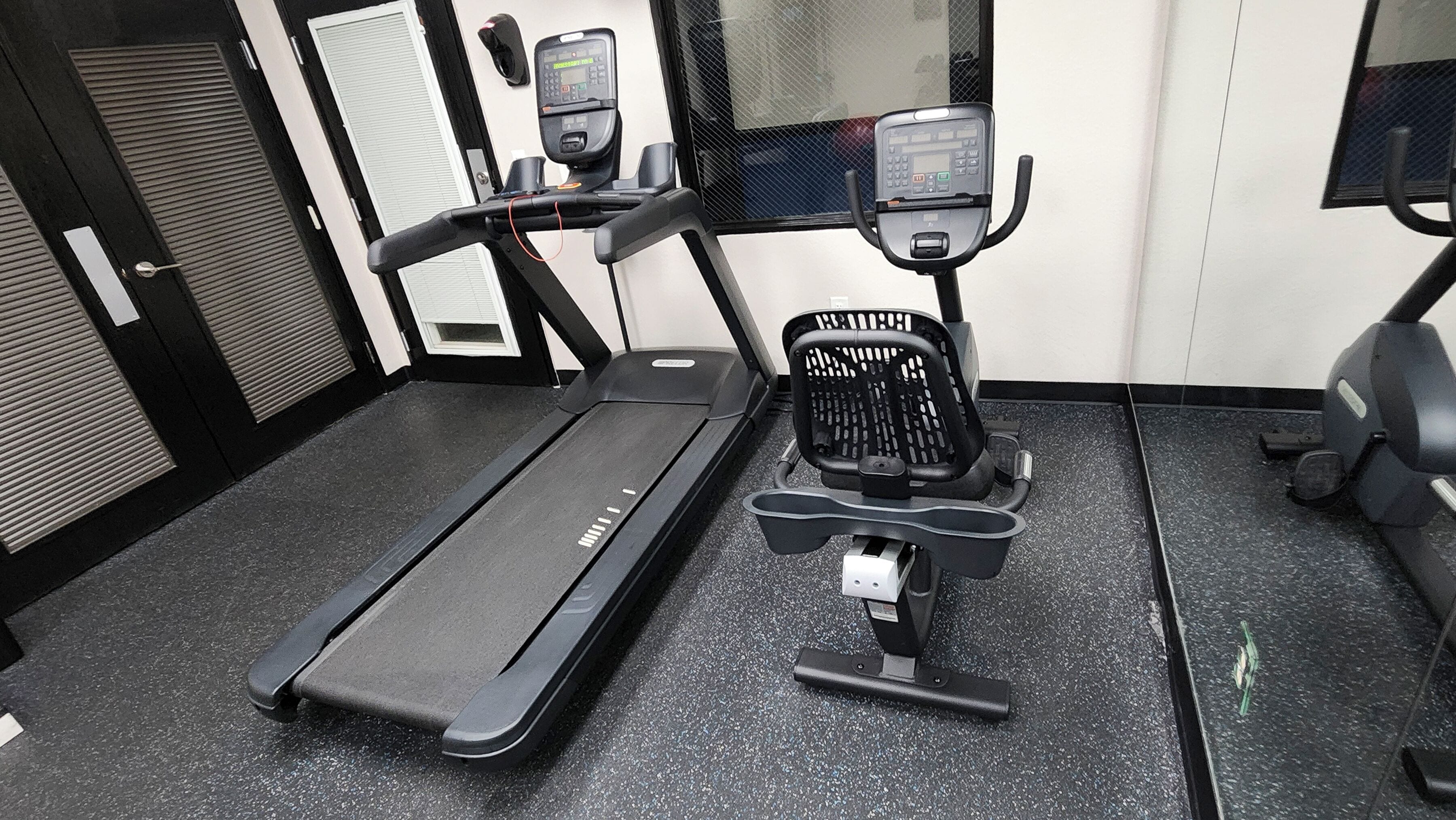 A gym with a treadmill, stationary bike, and exercise equipment.