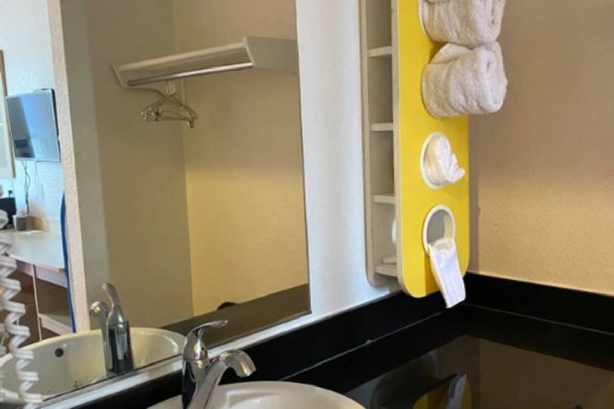 A bathroom with a mirror, sink, and towel rack.