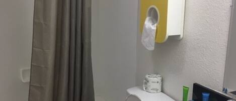 A bathroom with a shower curtain, a toilet, a sink, and a towel rack.