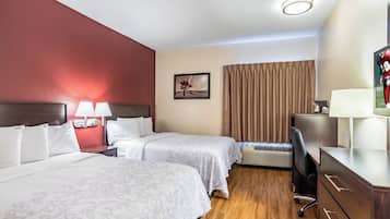 Une chambre d’hôtel avec deux lits, un bureau, une télévision et une fenêtre avec des rideaux.