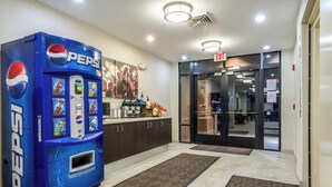 Un vestíbulo con una máquina expendedora de Pepsi, una recepción y una puerta de vidrio que da al interior.
