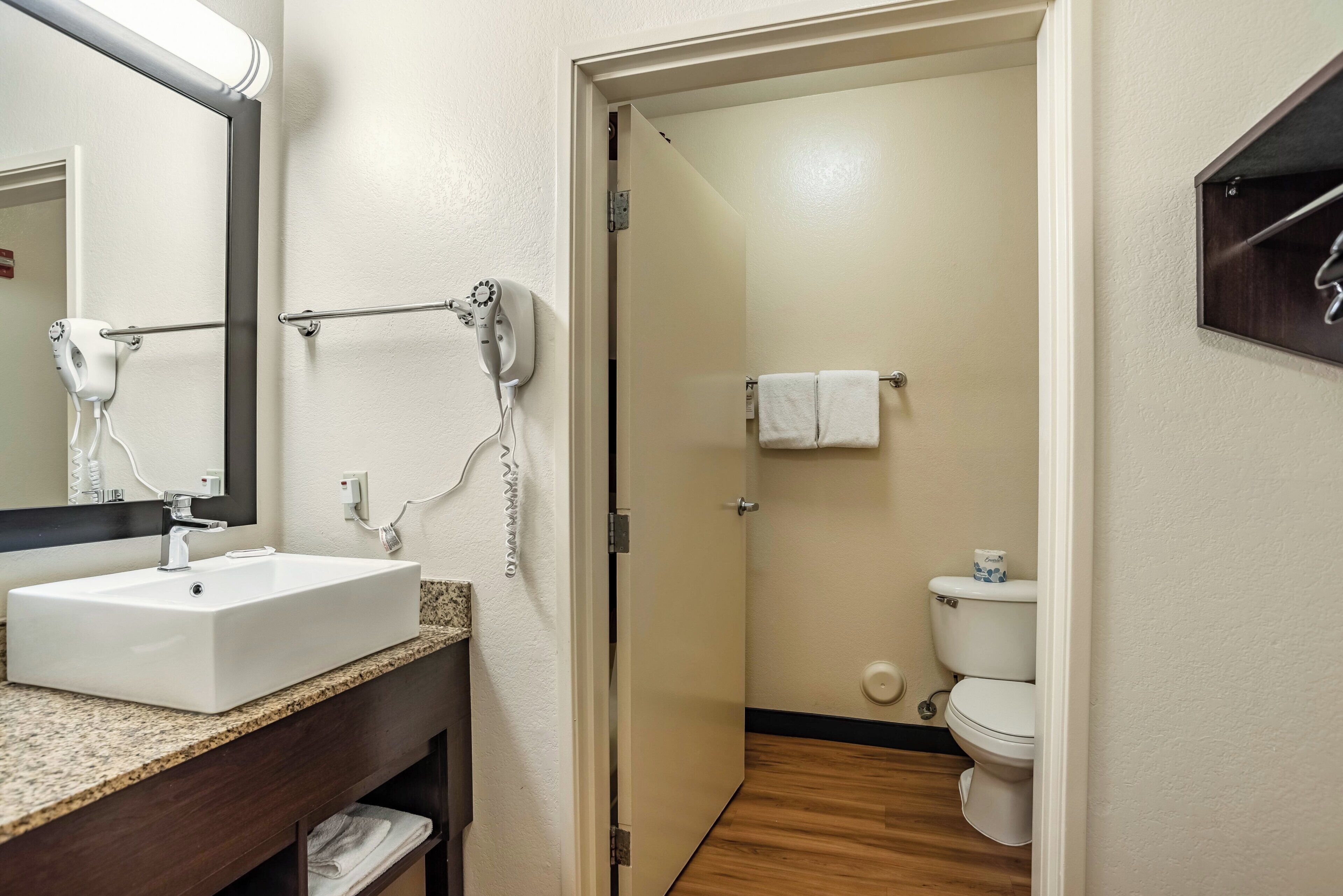 A bathroom with a sink, mirror, towel rack, and toilet.