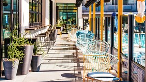 An outdoor seating area with chairs and tables, potted plants, and a wooden ceiling.