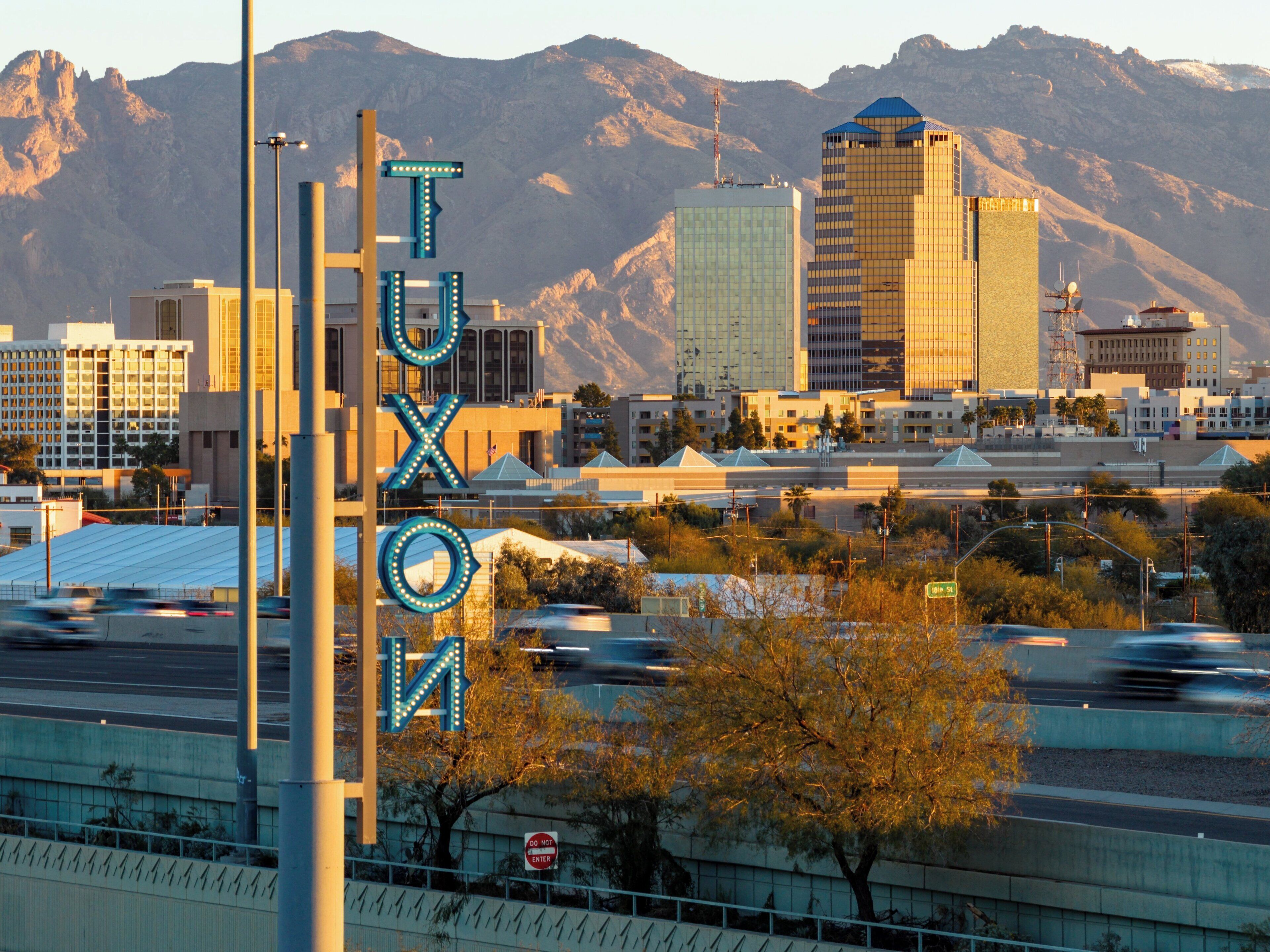 A cityscape with a prominent sign reading "TUXOM" and mountains in the background.