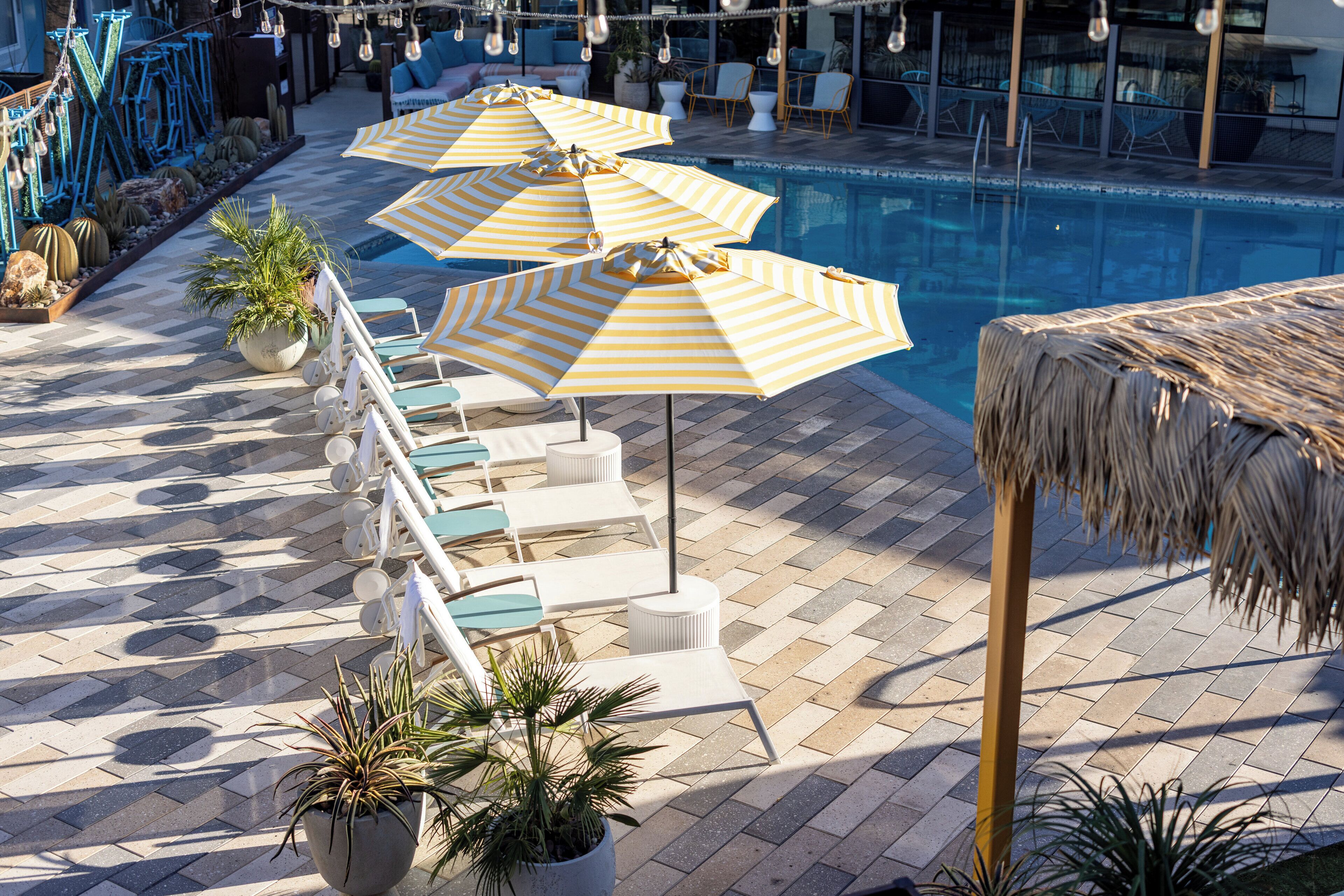 A poolside area with lounge chairs and striped umbrellas.