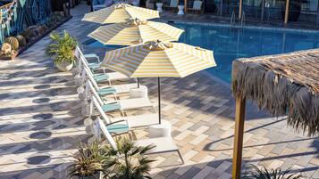 A poolside area with lounge chairs and striped umbrellas.