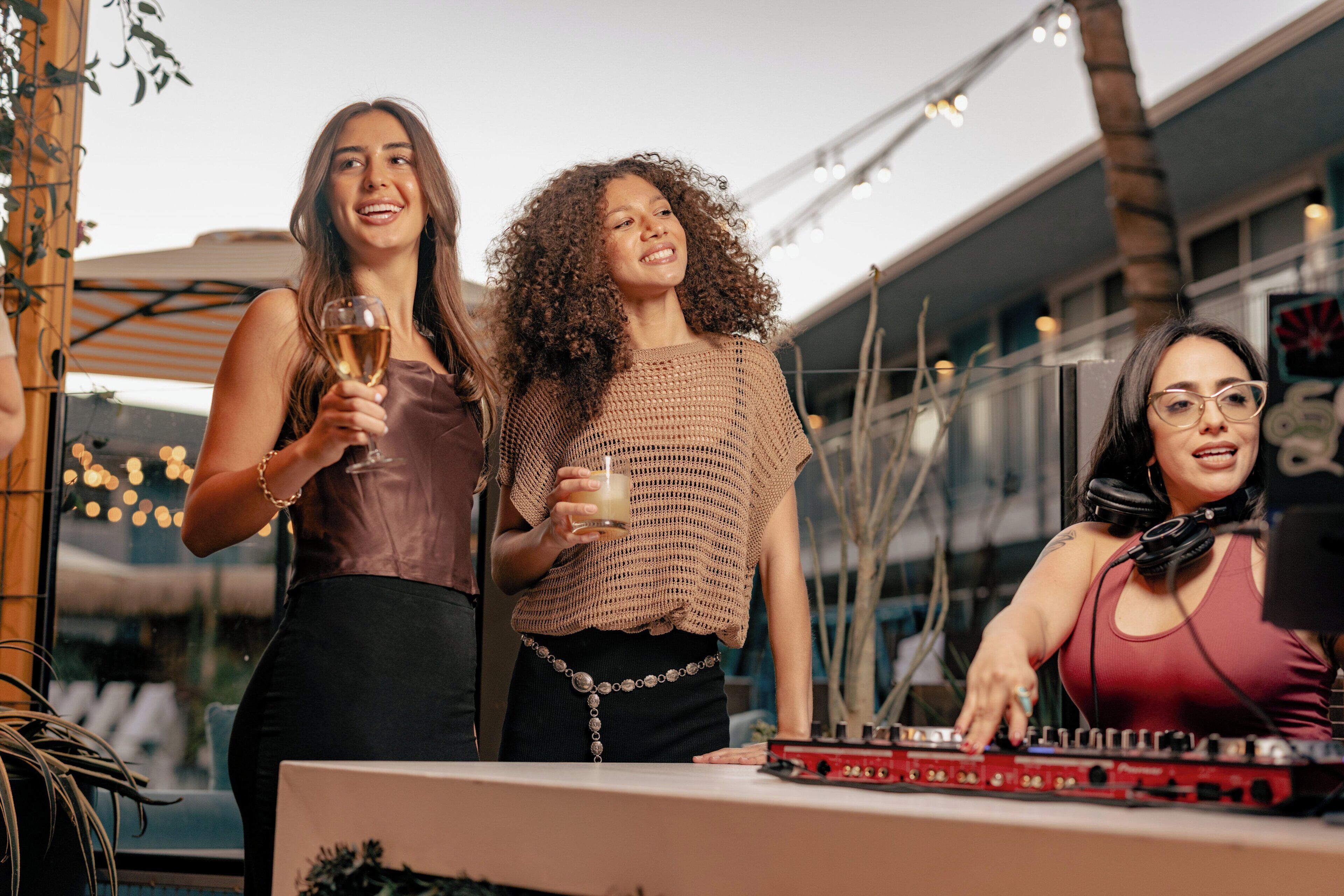 Tres personas de pie junto a una mesa con equipo de DJ.