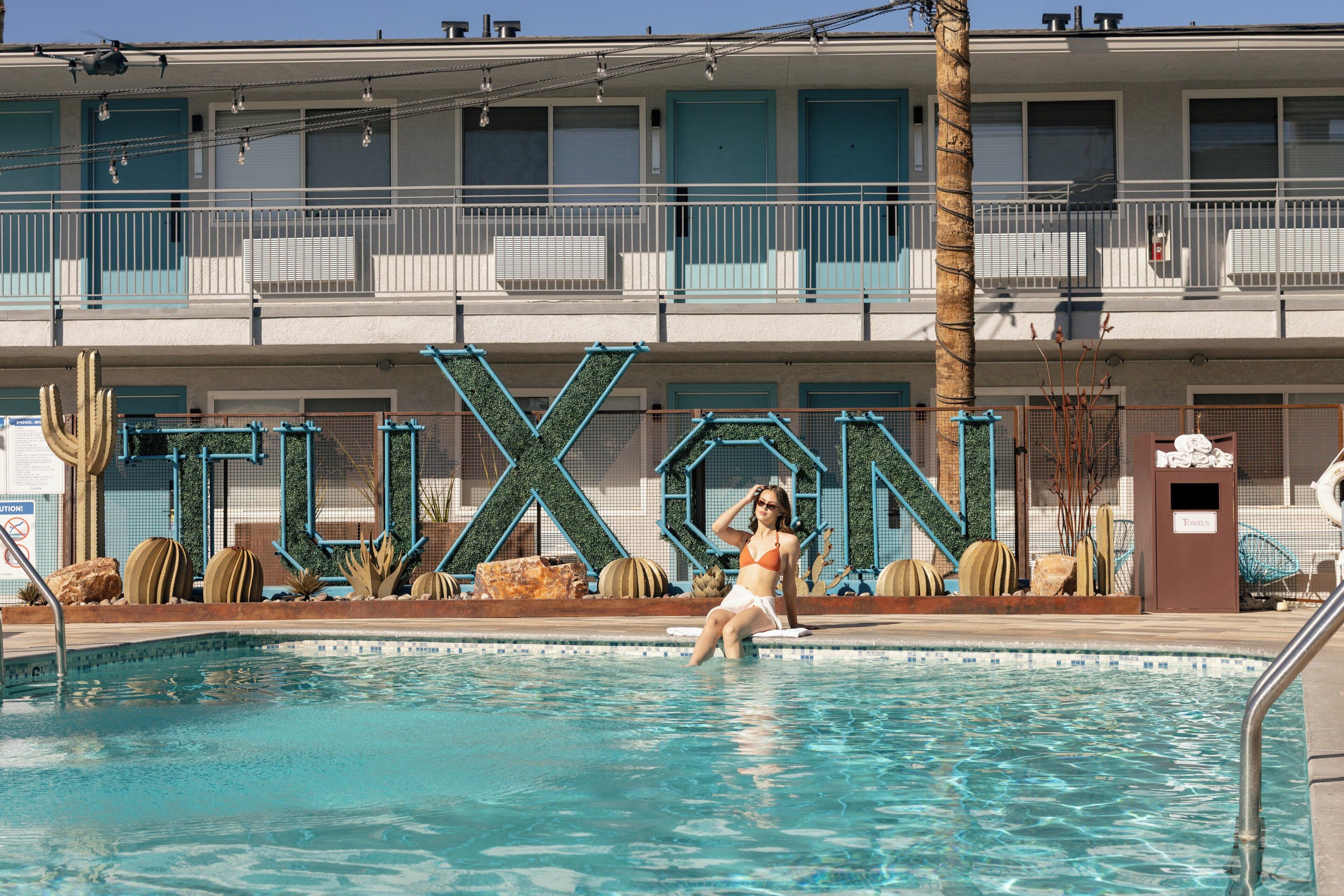 A swimming pool with a person in a bikini, surrounded by decorative rocks and plants.