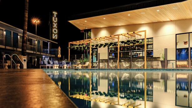 A modern hotel with a pool, lounge chairs, and a sign reading "TUXON". - voco The Tuxon by IHG (Tucson)