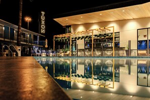 Un hotel moderno con piscina, sillas de descanso y un letrero que dice "TUXON".