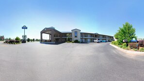 A Days Inn & Suites with a covered entrance, multiple parking spaces, and a clear sky. - Days Inn & Suites by Wyndham Pine Bluff (Pine Bluff)