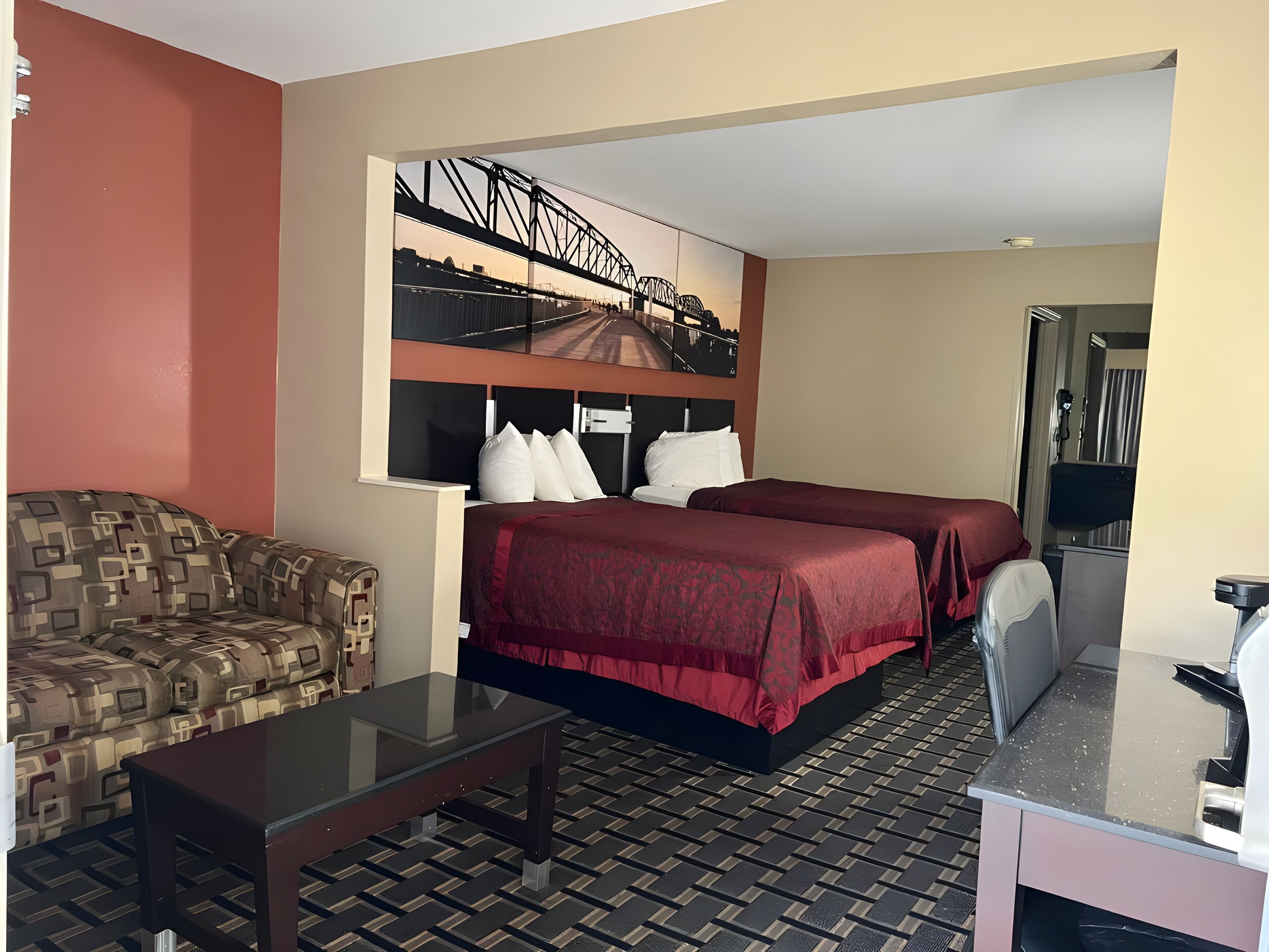 Habitación de hotel con cama, sofá, escritorio y una ventana grande con vista a la ciudad.
