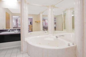 Un baño con una bañera grande, lavamanos doble y un espejo.