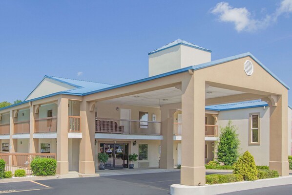 A two-story hotel with a covered entrance, balconies, and a parking lot. - Days Inn & Suites by Wyndham Pine Bluff (Pine Bluff)