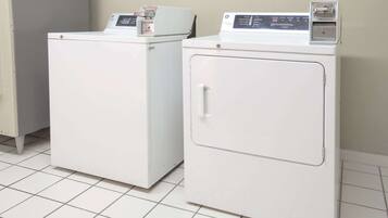 Two white front-loading washing machines in a laundry room with tiled flooring.